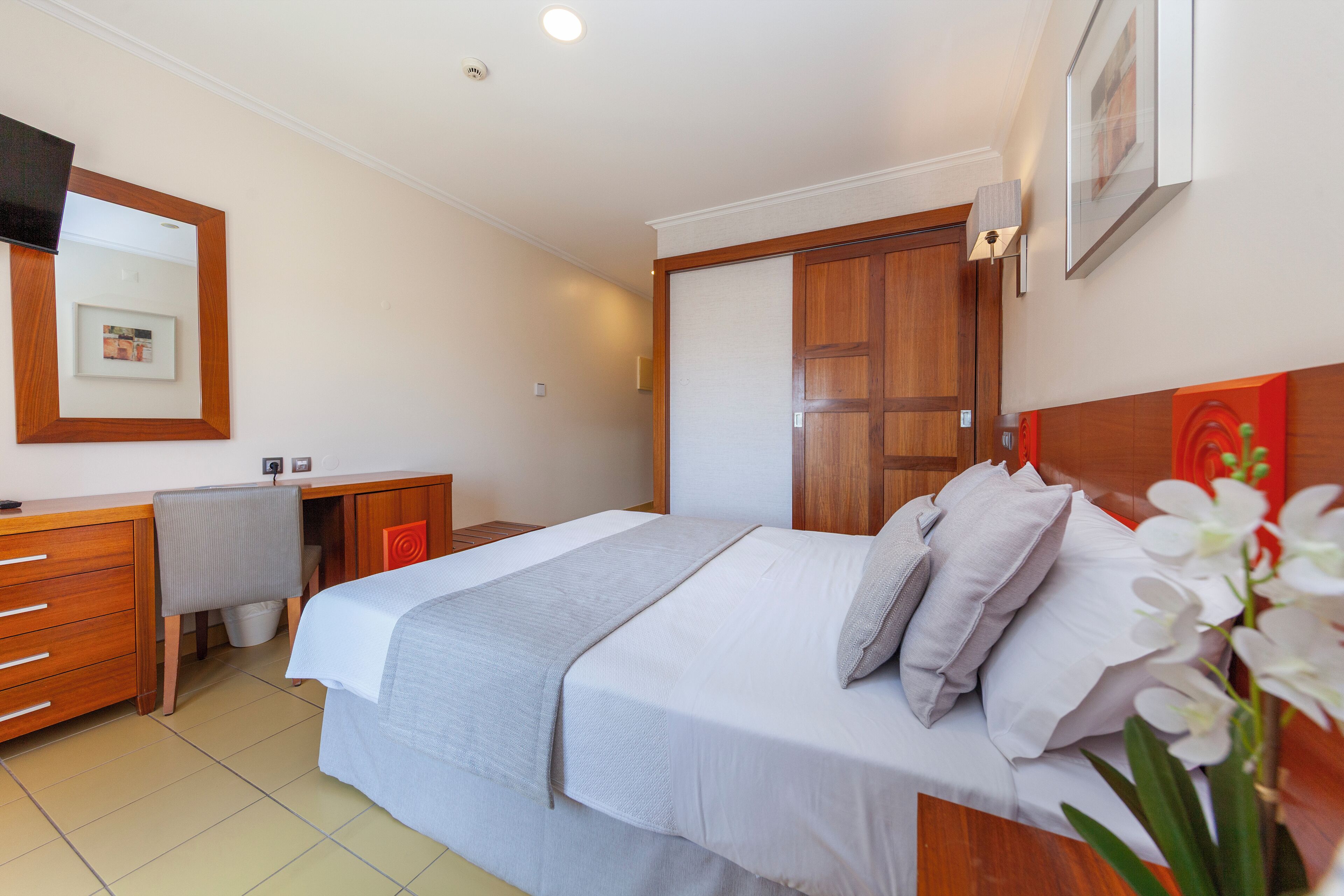 A bedroom with a bed, a desk, and a chair.