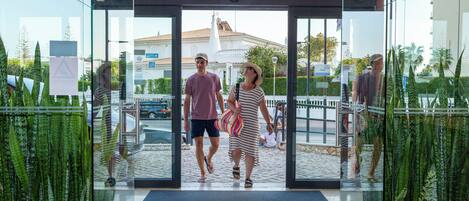 A glass entrance with a welcome mat to a building.
