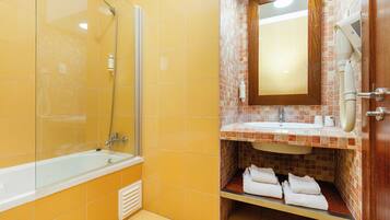 A bathroom with a bathtub, a shower, a sink, and a mirror.