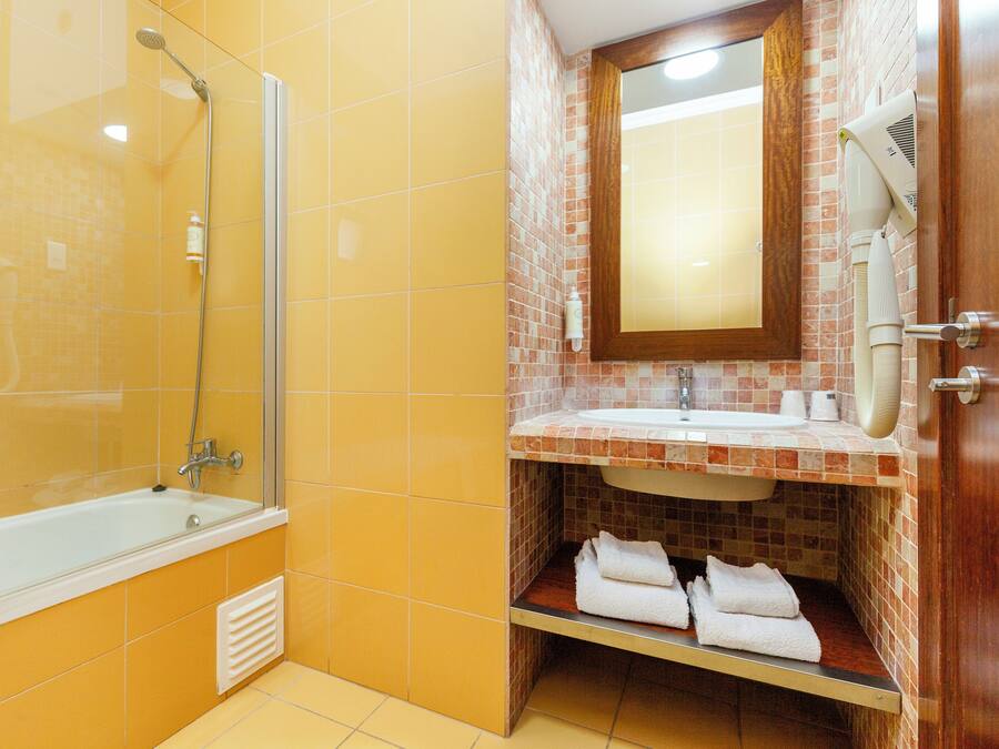 A bathroom with a bathtub, a shower, a sink, and a mirror.