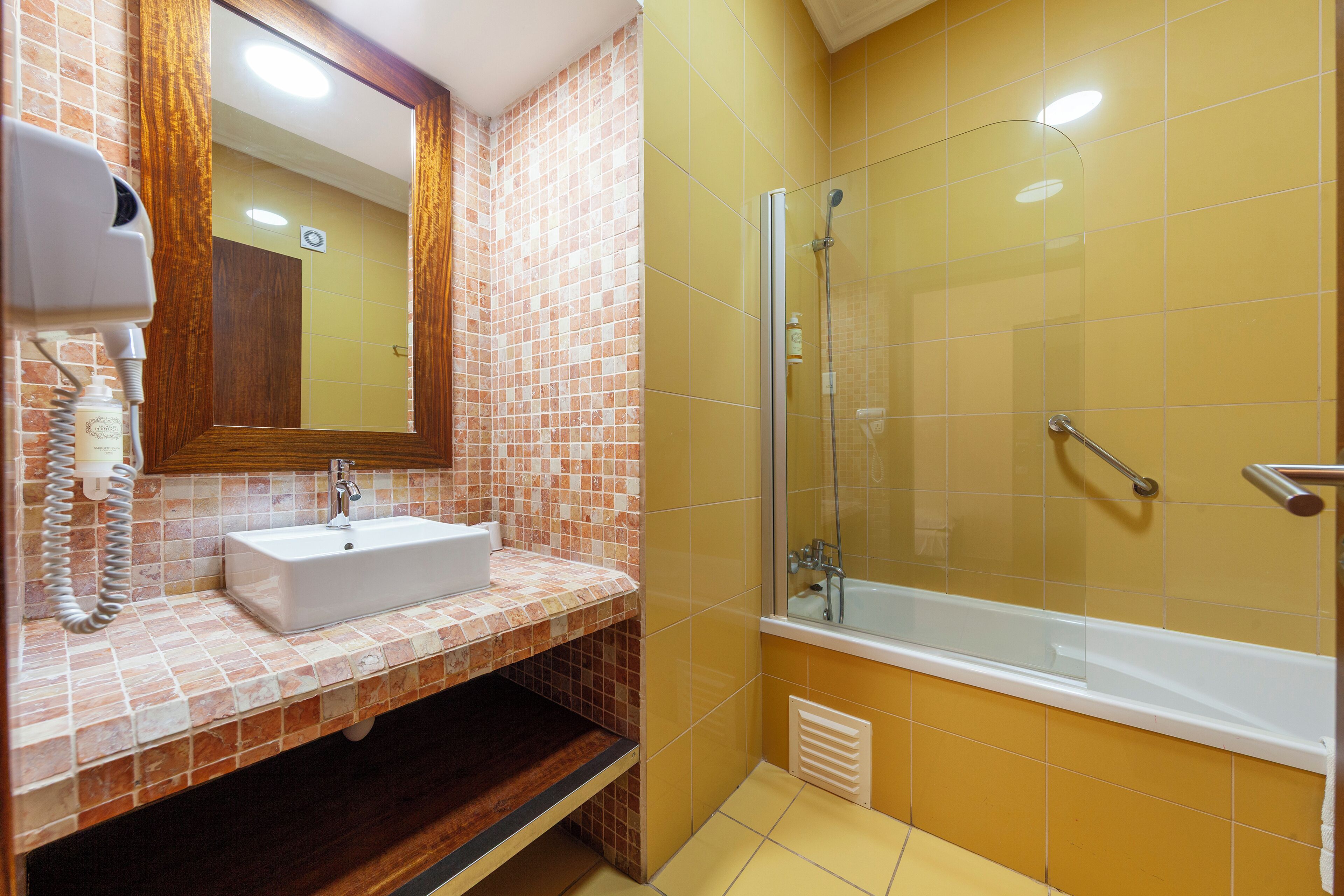 Un baño con lavamanos, espejo y ducha.
