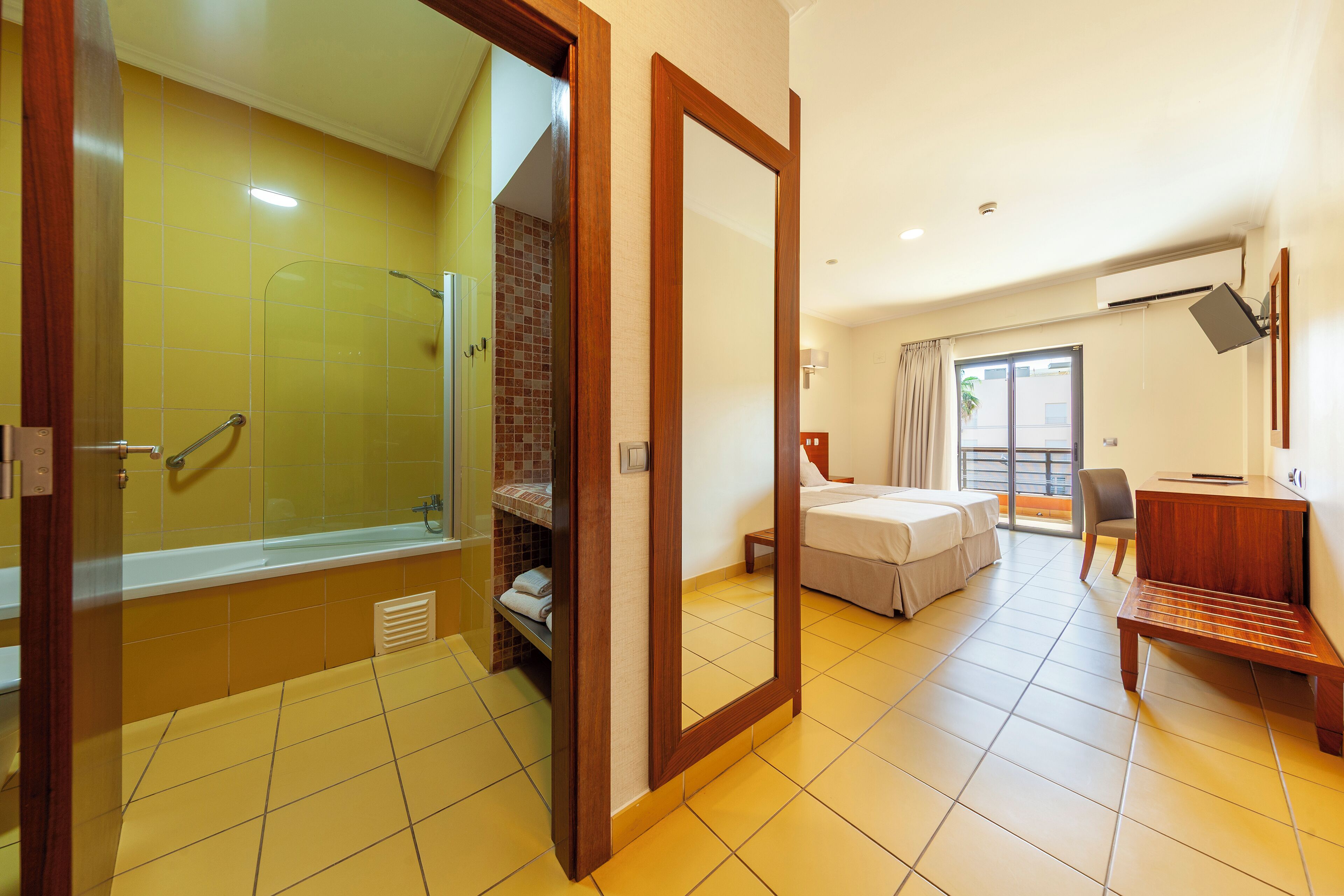Habitación de hotel con ducha, cama, escritorio y vistas al exterior.
