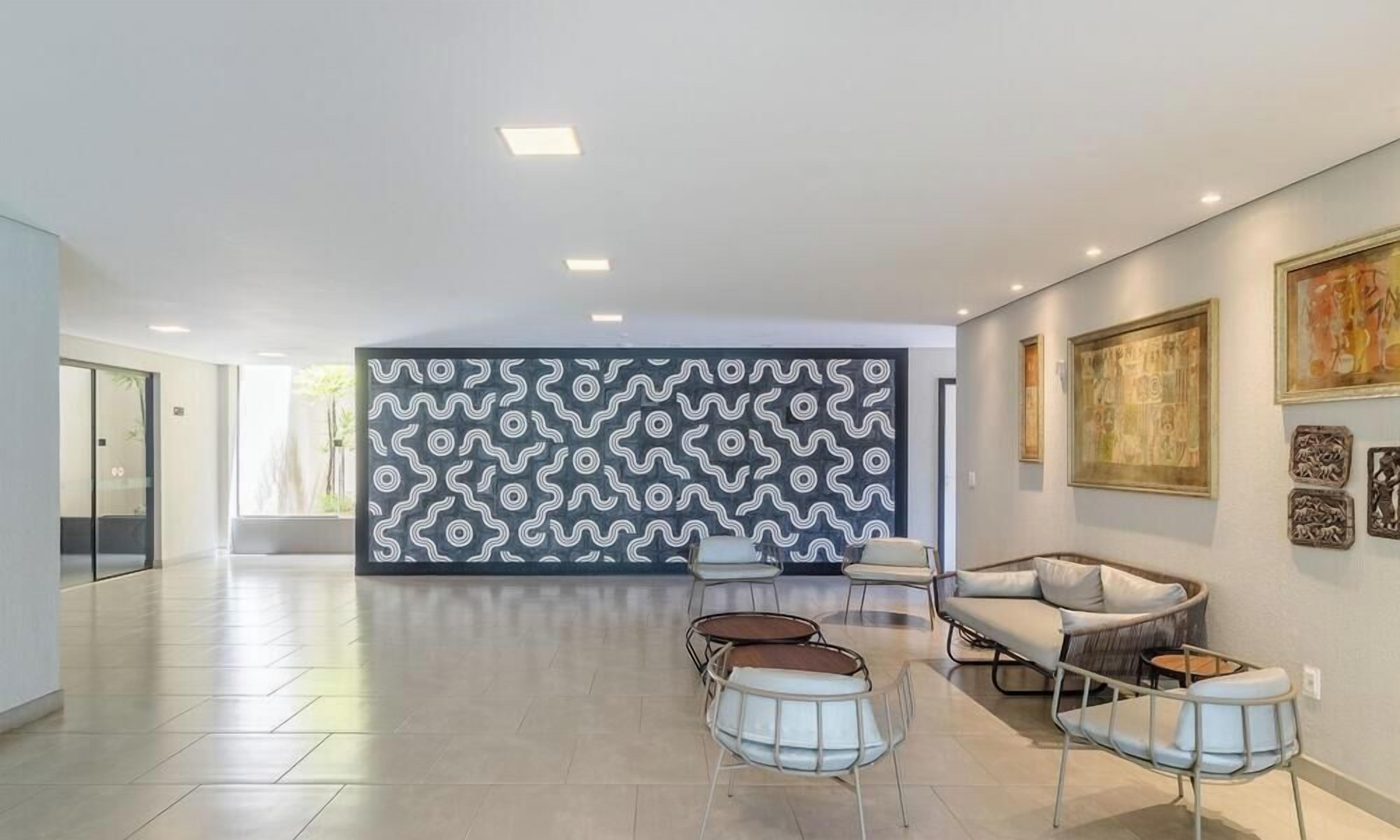 Un hall d’entrée spacieux, agrémenté d’un mur décoré de motifs, de sièges modernes et d’œuvres d’art.