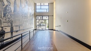 Un pasillo con un mural, una escalera y vistas al exterior.