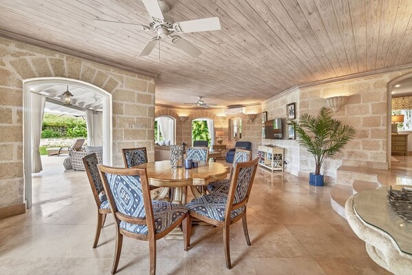 A dining area with a round table, chairs, and a ceiling fan.