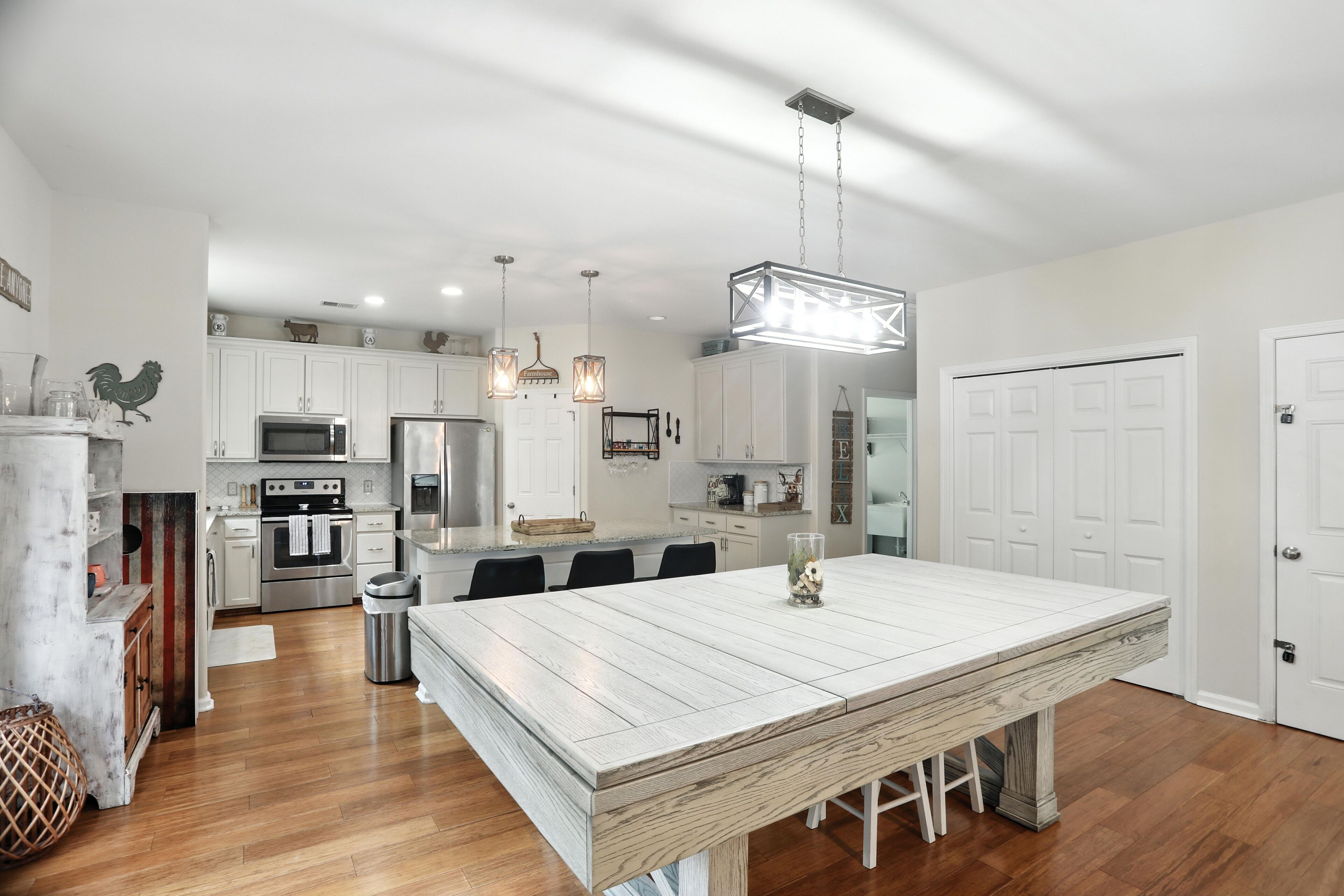 A modern kitchen with white cabinetry, stainless steel appliances, and a large island with seating.