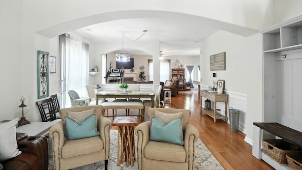 A spacious living room with a high ceiling, a dining area, and a kitchen in the background.