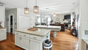 A spacious kitchen with a central island, pendant lighting, and a view into the dining area.