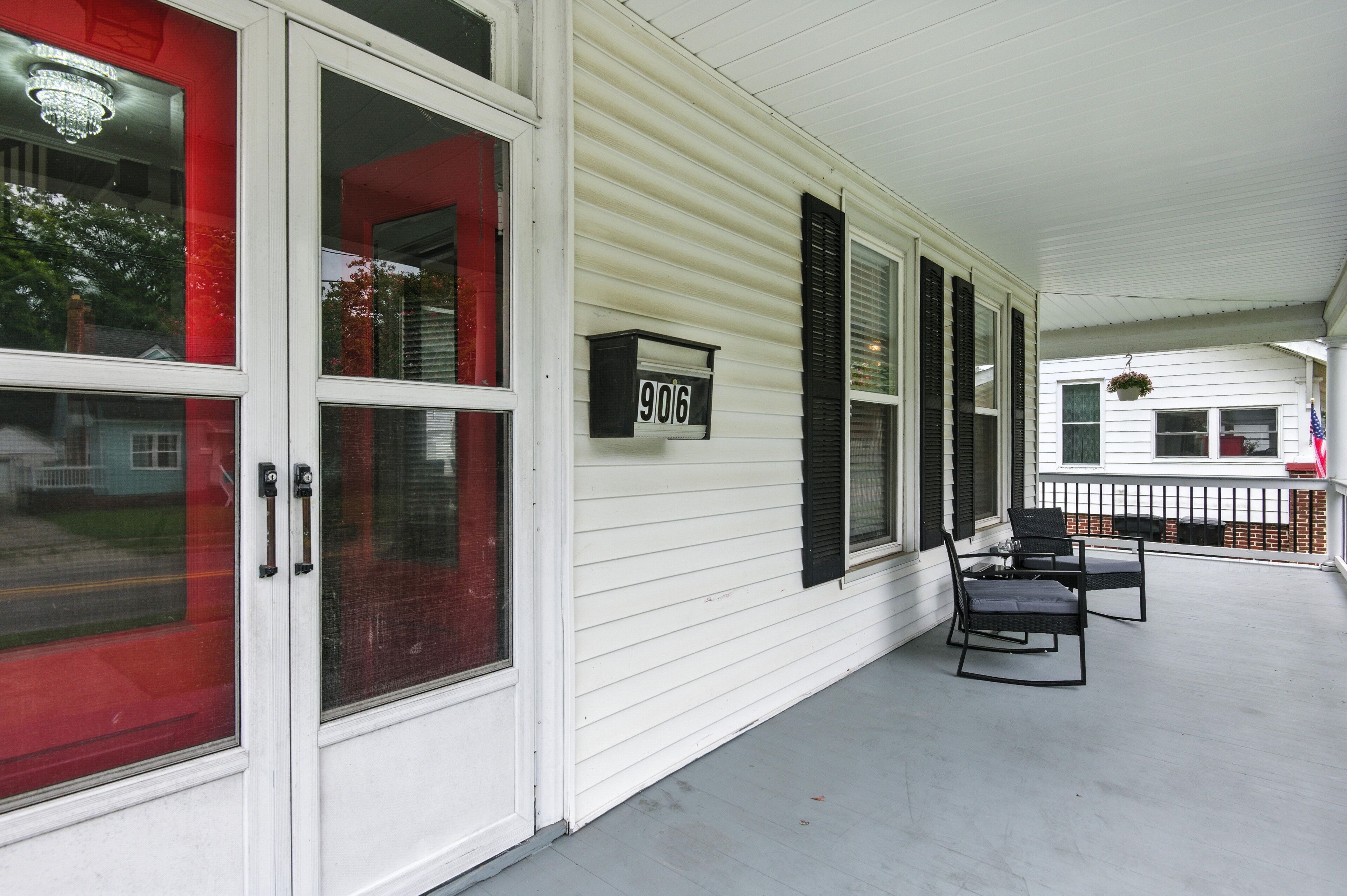 A covered porch with a white exterior, black shutters, and a number sign '906'.