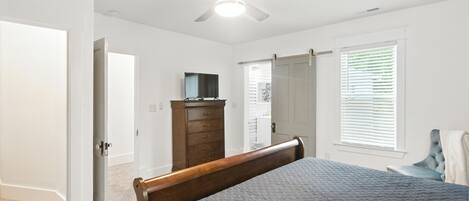A bedroom with a bed, a dresser, a ceiling fan, and a window with blinds.