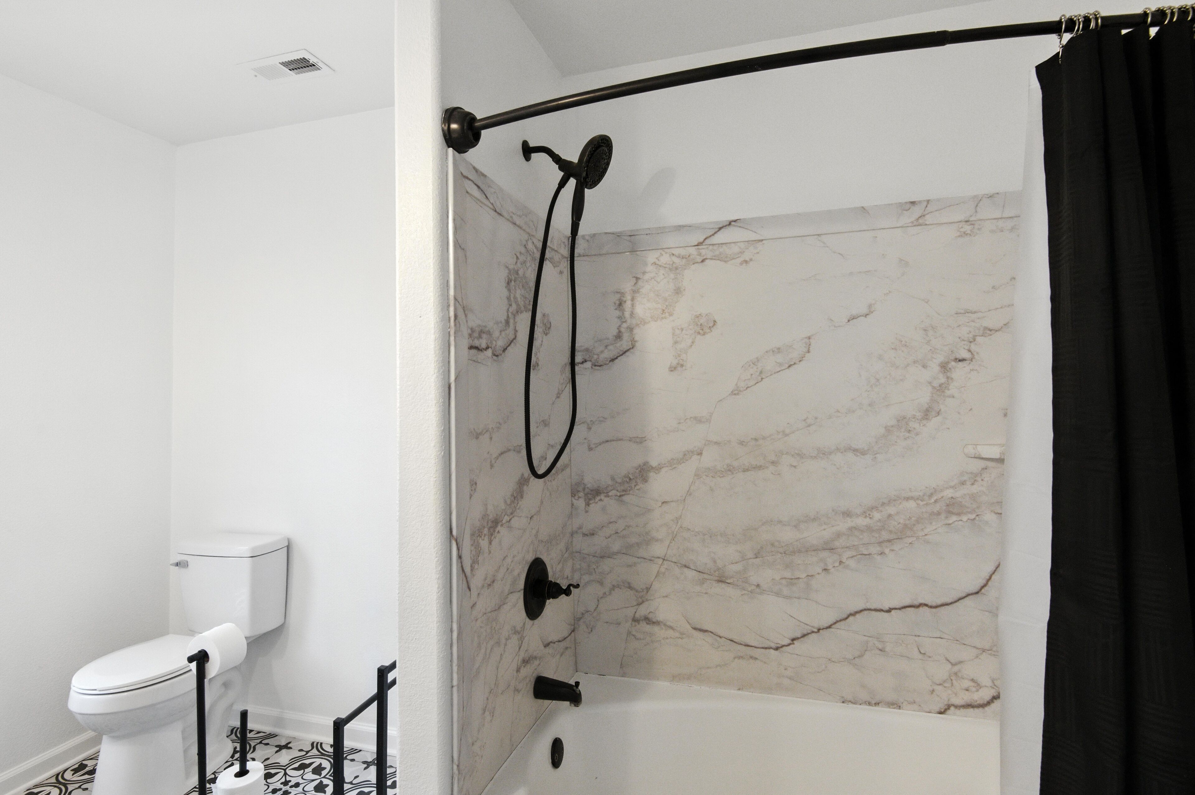 Een badkamer met een douche, toilet en marmeren wanden.