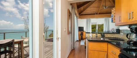 A spacious kitchen with wooden cabinets and a large window overlooking the sea.