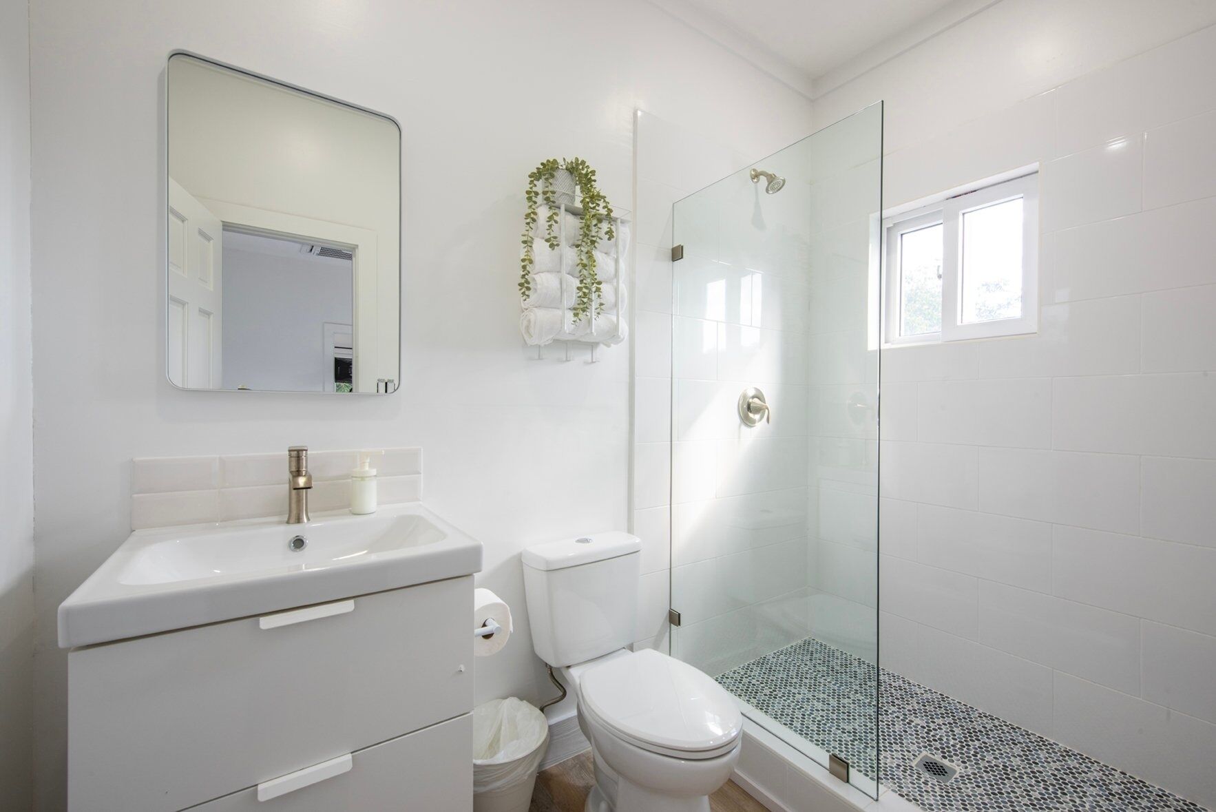 A modern bathroom with a white sink, toilet, and glass shower enclosure.