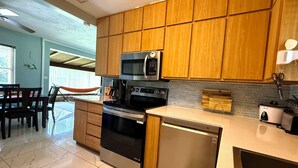 Une cuisine moderne avec des meubles en bois, des appareils électroménagers en acier inoxydable et un sol carrelé.