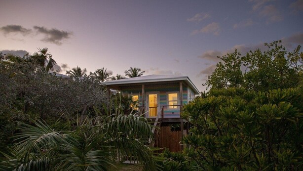Ein Haus mit überdachter Veranda, umgeben von üppiger tropischer Vegetation.
