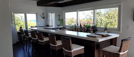 A modern kitchen with a large island, bar stools, and a view of the outdoors.