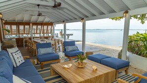 An outdoor seating area with blue cushioned sofas and a wooden coffee table, overlooking a beach. - Beehive Harbour Island. Luxury Dream World On The Bay. Private D 5 Bedroom Home (Dunmore Town)