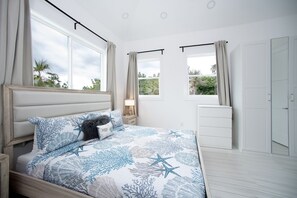 A bedroom with a bed, a nightstand, a dresser, and a door. - Silver Palms - Brand New Designer Home On Banks Road 2 Bedroom Home (North Palmetto Point)