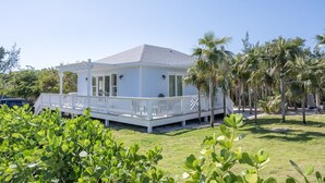 Una casa blanca con porche cubierto y patio cercado.