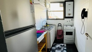 Eine kompakte Küche mit Kühlschrank, Spüle, Herd und Telefon.