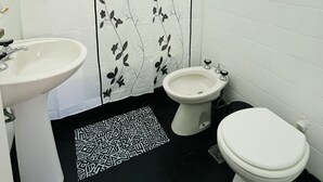 Ein Badezimmer mit einem weißen Waschbecken, einem Bidet und einer Toilette.