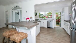A modern kitchen with white cabinetry, a central island, and a stainless steel refrigerator.