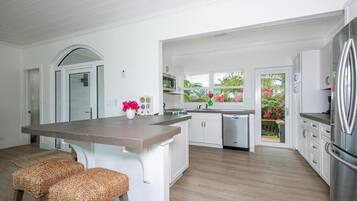 A modern kitchen with white cabinetry, a central island, and a stainless steel refrigerator.