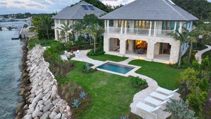 Una casa grande con piscina, patio y vista al agua.