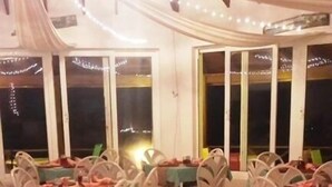 Un espace de restauration en plein air doté de plusieurs tables et chaises, recouvert d’un auvent blanc et illuminé de guirlandes lumineuses.