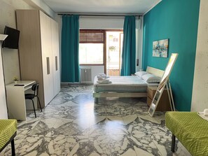 A hotel room with a bed, a desk, a chair, a radiator, and a window with curtains. - Spacious 3 Bedrooms with Balcony&AC in Vaticano (Roma)