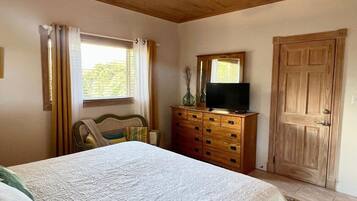 Un dormitorio con una cama, un aparador de madera, un televisor y una puerta.