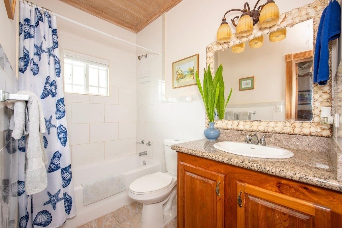 Een badkamer met een bad, toilet, wastafel en een spiegel met decoratieve lijst.