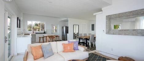 A modern living room with a sofa, coffee table, and dining area with chairs and a table.
