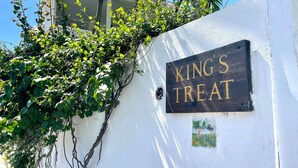 A white wall with a sign that reads "KING'S TREAT". - Hibiscus Hill Kings Treat - Ultimate Island Style House W/pool 3 Bedroom Home (Dunmore Town)