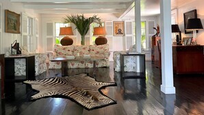 A spacious living room with a sofa set, a zebra rug, and a large plant. - Hibiscus Hill Kings Treat - Ultimate Island Style House W/pool 3 Bedroom Home (Dunmore Town)