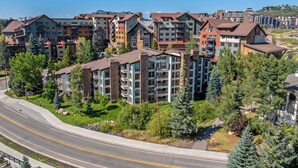 A multi-story residential building with balconies and a road in the foreground. - Dulany Style+Comfort~Base Area Condo~Best Location (Steamboat Springs)