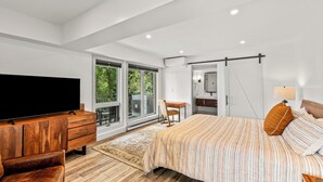 A modern bedroom with a large bed, a wooden dresser, a flat-screen TV, and a sliding glass door leading to a balcony. - Dulany Style+Comfort~Base Area Condo~Best Location (Steamboat Springs)