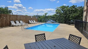 Un jardin avec une piscine, des chaises longues et une table.