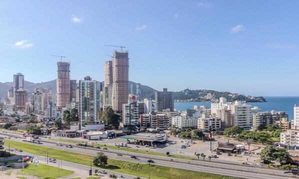 A cityscape with high-rise buildings, a highway, and a coastal view. - 2BR Apt w/ BBQ & View 550m From Beach - Omc1303 (Itapema)