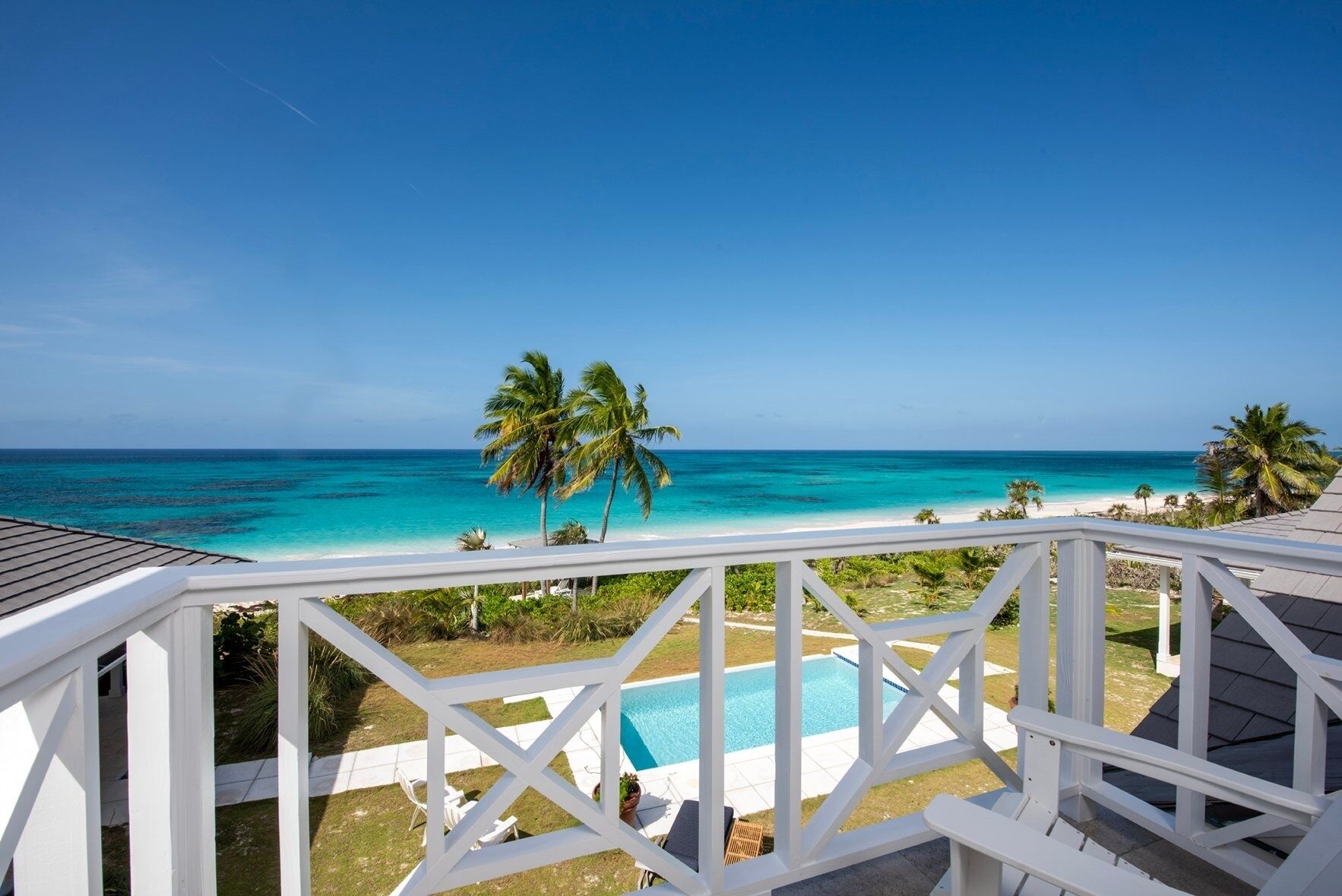 A pool with a view of the ocean and palm trees.