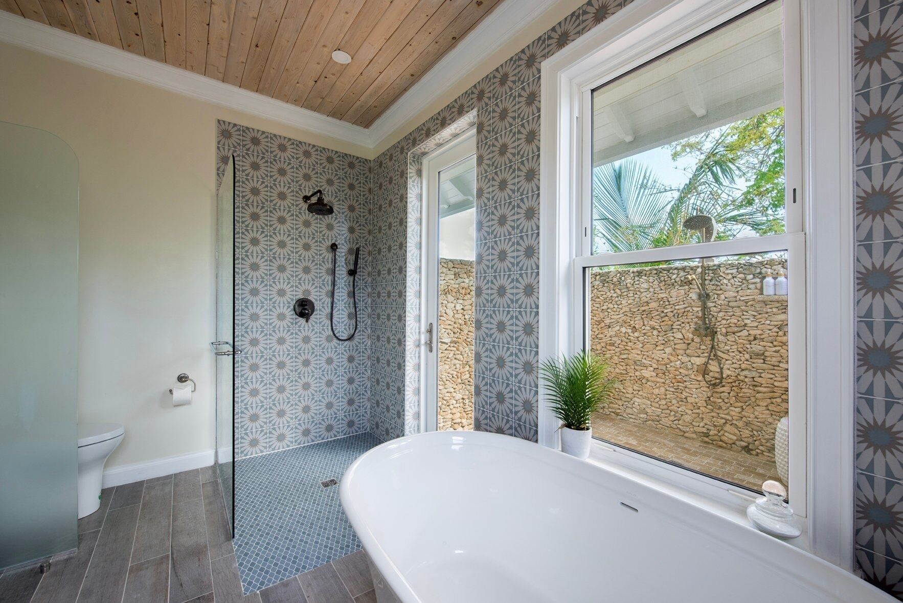 A modern bathroom with a freestanding bathtub, a shower with a rain showerhead, and patterned tiles.