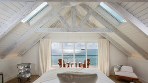 A bedroom with a large bed, a view of the ocean, and a skylight. - Touch Of Class Cottage - A Caribbean Beachfront Cottage 2 Bedroom Cottage (Savannah Sound)