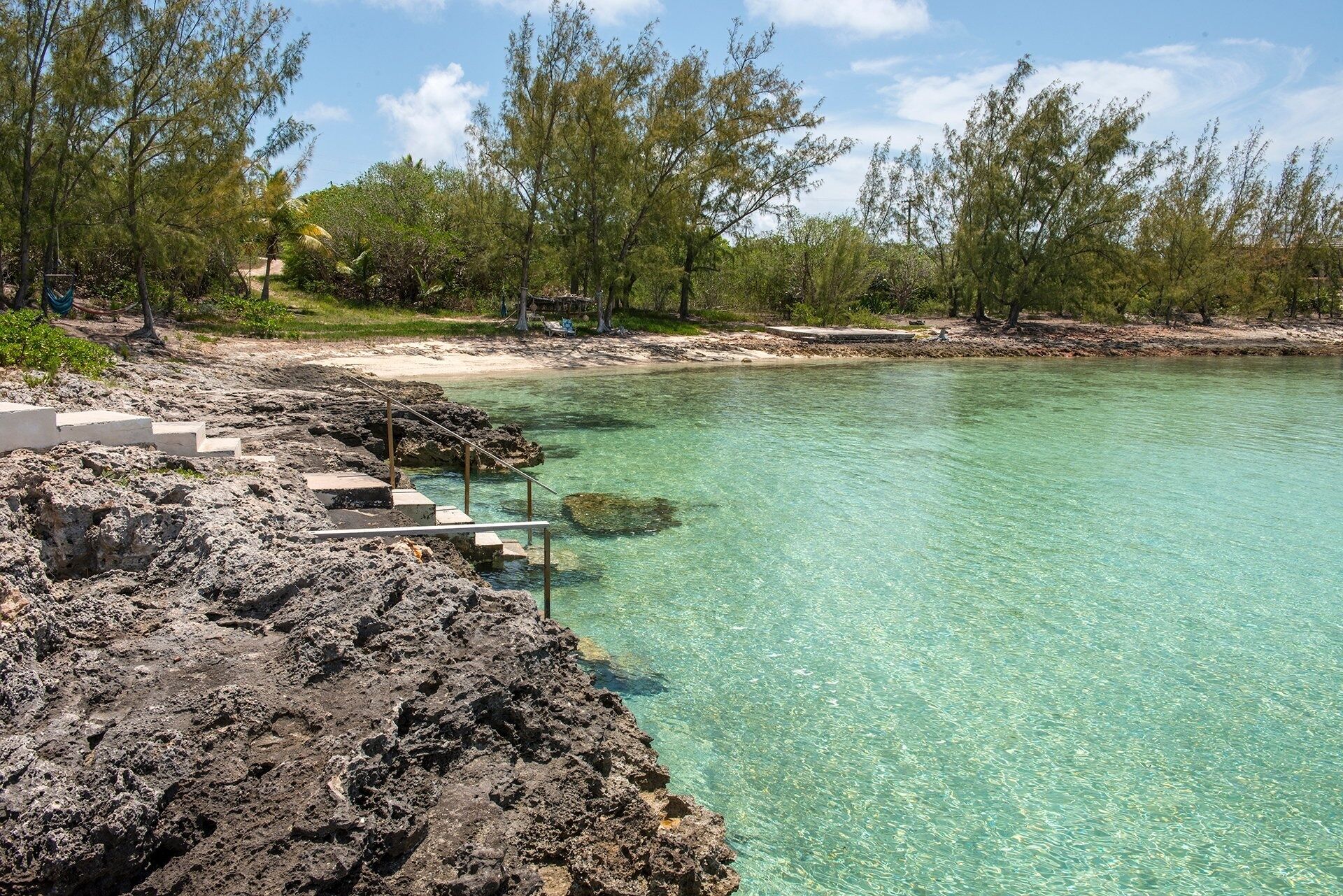 A clear turquoise sea with rocky shorelines and steps leading into the water.