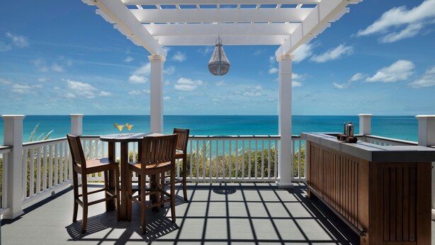 A covered outdoor seating area with a view of the ocean, a hanging light fixture, and a bar counter. - Buttonwood Reserve Compound - Compound W/beach, Pool, Pickleball 17 Bedroom Condo (James Cistern)