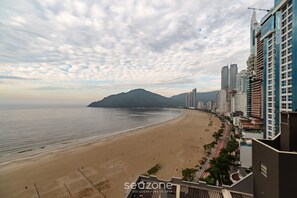 A coastal cityscape with a wide beach, high-rise buildings, and a mountain in the distance. - 2BR Seafront apt W/garage in BC Nvi501 (Balneário Camboriú)