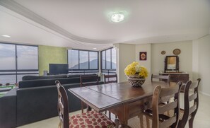 Una sala de estar moderna con comedor, ventanas amplias y vistas a montañas.
