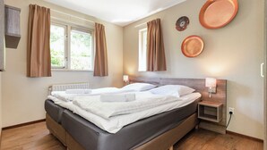 Een tweepersoonsbed met witte lakens, een houten hoofdbord en een nachtkastje met een lamp.