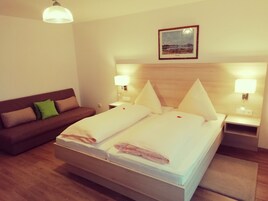 Quarto de hotel com cama, mesa de cabeceira, luminária, quadro na parede e sofá.