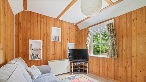 Un salon chaleureux avec un décor en bois, un canapé, un téléviseur et des étagères à livres.