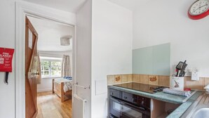 Eine kleine Küche mit Einbauofen, einer Arbeitsplatte und einem Fenster mit Vorhängen.